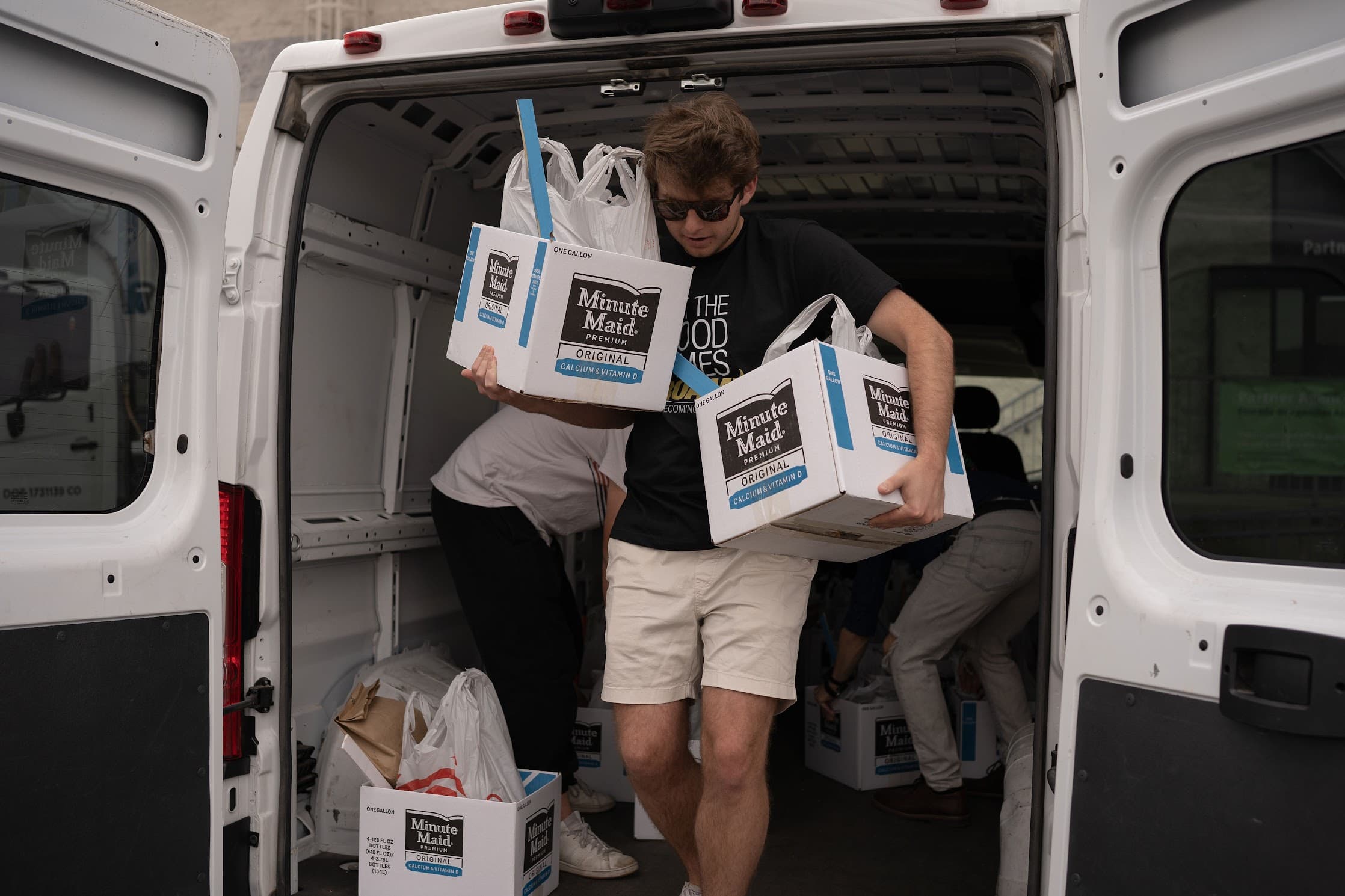 Volunteers unloading boxes of donated juice from a van